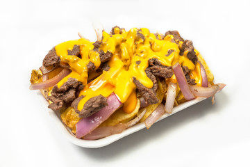 Peruvian street food:  Beef salchipapas with cheddar cheese served on a white plate
