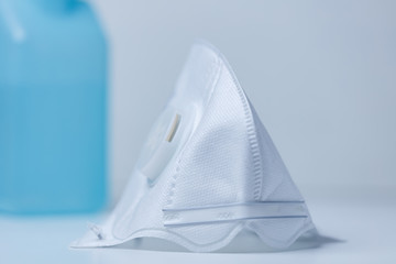 White antiviral medical mask on a background of blue sanitizer