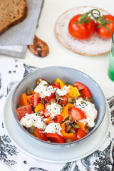 Fresh healthy salad with tomatoes, grilled pepper, cheese, pumpkin seeds and black sesame.