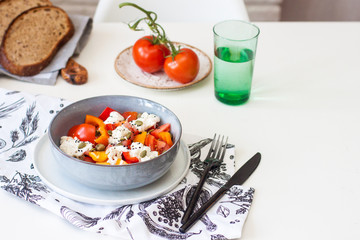 Fresh healthy salad with tomatoes, grilled pepper, cheese, pumpkin seeds and black sesame.