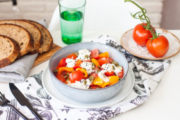Fresh healthy salad with tomatoes, grilled pepper, cheese, pumpkin seeds and black sesame.