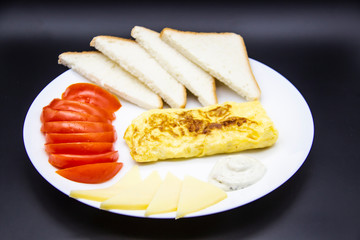 Amazing breakfast with tasty omelet, tomatoes, cheese, bread and sauce on the white plate. Delicious omelet made like rolle, other ingredients. Tasty and diet food. Healthy meal for breakfast or lunch