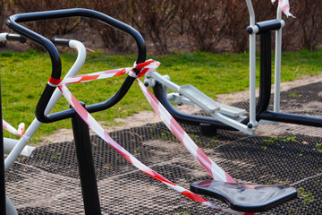 Outdoor sports equipment is tied up with barrier tapes during COVID-19 or coronavirus quarantine or pandemics, repair. Prohibiting people from using the street gym.