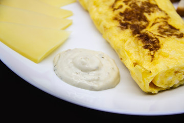 Amazing breakfast with tasty omelet, tomatoes, cheese, bread and sauce on the white plate. Delicious omelet made like rolle, other ingredients. Tasty and diet food. Healthy meal for breakfast or lunch