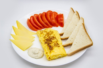 Amazing breakfast with tasty omelet, tomatoes, cheese, bread and sauce on the white plate. Delicious omelet made like rolle, other ingredients. Tasty and diet food. Healthy meal for breakfast or lunch