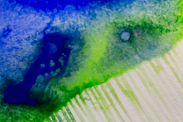 Watercolor paints spread on wet white paper in various combinations of green and blue paint, strokes symbolize rain. Concept of a picturesque watercolor rain background.