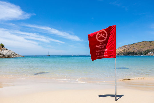No Swimming Here. Danger sign at the beach,on red flag in English and Thailand and China and Russian
