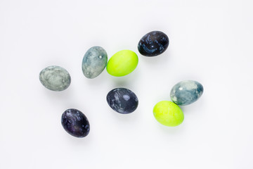 Easter eggs painted in different shades of blue and green lie chaotically on a white background