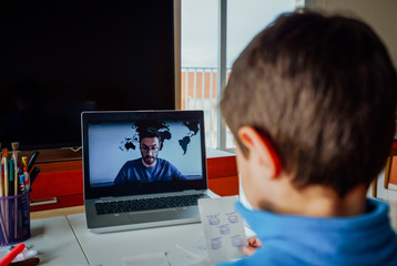 Boy studying homework during his online lesson at home, social distance during quarantine. Self-isolation and e-learning concept caused by coronavirus pandemia