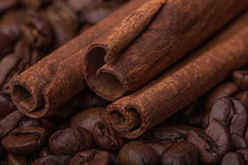 Three sticks of cloves against the background of coffee beans, close-up