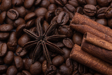 Three cinnamon sticks and a star anise against the background of coffee beans