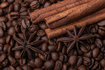 Three cinnamon sticks and a star anise against the background of coffee beans