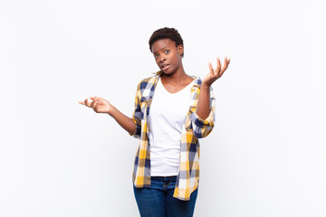 young pretty black womanshrugging with a dumb, crazy, confused, puzzled expression, feeling annoyed...