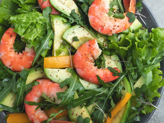 Fresh vegetarian green salad with avocado, shrimp and arugula close up, healthy food