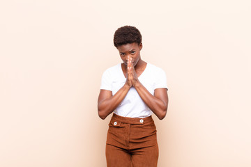 young pretty black womanfeeling worried, hopeful and religious, praying faithfully with palms...