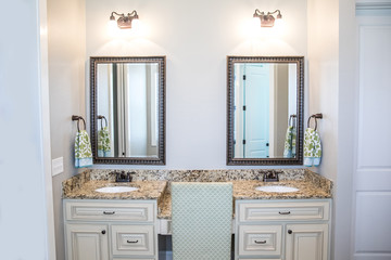 Large neutral cream colored master bathroom with double sinks, two mirrors and a granite countertop...