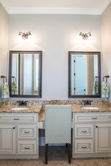 Large neutral cream colored master bathroom with double sinks, two mirrors and a granite countertop in a new construction modern home