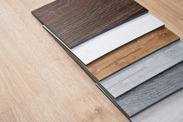Sample catalog of luxury vinyl floor tiles with a new interior design for a house or floor on a light wooden background. Copy space.