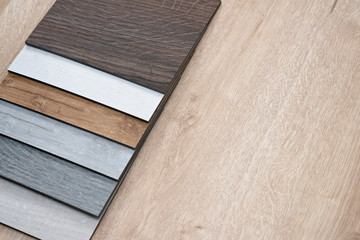 Sample catalog of luxury vinyl floor tiles with a new interior design for a house or floor on a light wooden background. Copy space.