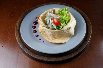Salad in white bread on a blue plate.