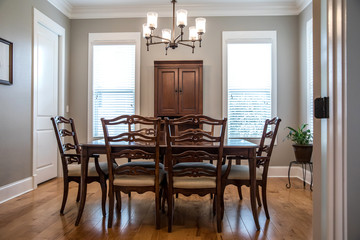Formal Dining room with a set of wood table and chairs and a chandelier with windows and natural lights and hardwood floors