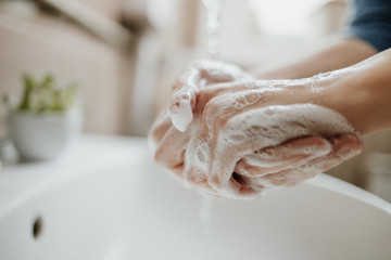 Closeup of a woman washing her hands in bathroom to prevent Covid-19 viral infection. Recommended...