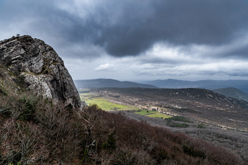 Fototapeta na wymiar The mountain over grotto of Mary Magdalene at cloudy weather, clouds over a valley, a dry grass