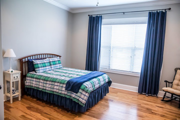 Light gray teenage boy bedroom with a wood bed and plaid bedspread and curtains in shades of blue, green and white