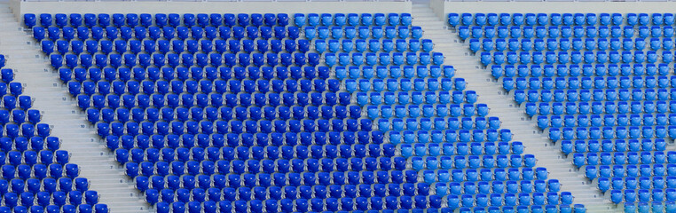 Naklejka premium Empty blue and dark-blue seats in the stadium before the match