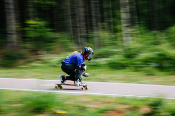 Obraz premium crazy athlete on a longboard rides along a forest road with turns