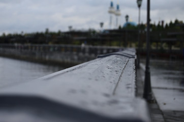 promenade railings with raindrops close-up going into the distance amid lanterns overcast sky