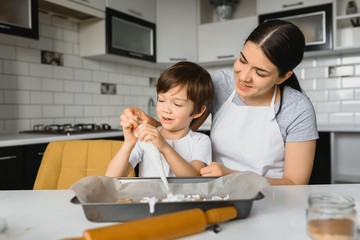 Happy mother and child in kitchen preparing cookies