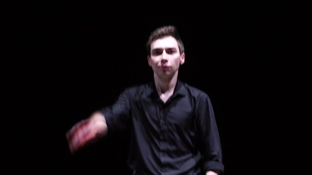 Happy man in black shirt resting and dancing on black background