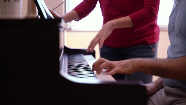 Student practicing index hands on musical instrument. Music concept. Unrecognizable man learning piano lessons at home. Detail of teacher explaining correct hands position of piano keyboard.