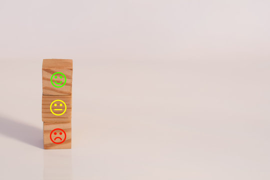 Wooden cubes with the image of smile face emotion. Three traffic lights colored smileys. Customer survey feedback, customer rating concept