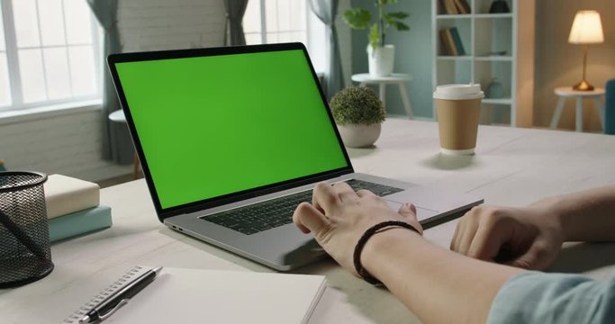 Close up shot of hands of freelancer working with chroma key green screen laptop, using trackpad scrolling through website - technology concept 4k video template
