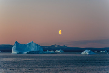 Beautiful moonrise in Greenland. Iceberg at sea.