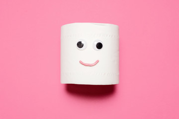 Happy smiling full toilet paper roll with googly eyes and mouth on a pink background with copy...