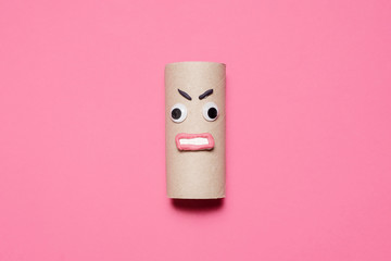 Empty angry toilet paper roll with googly eyes and mouth on a pink background with copy space and room for text 