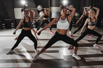 Fotobehang Sportschool Women in black and white sportswear on a real group body Combat workout in the gym train to fight, kickboxing with a trainer  © amixstudio