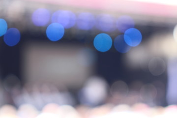 Abstract defocused bokeh lighting on stage during a concert with audience as a background with space in the middle.