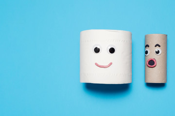 Happy smiling full toilet paper roll next to a surprised empty toilet roll with googly eyes and mouths on a blue background with copy space and room for text with a right side composition.