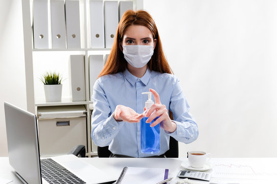 Business Woman In A Mask Washes Hands With Gel In The Workplace