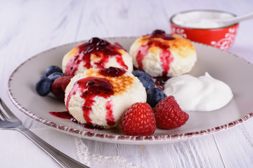 Tasty cheesecakes with berry souce, sour cream and fresh blueberries and raspberries