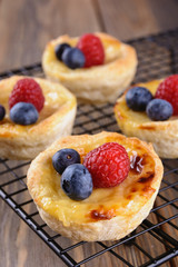 Small puff pastry tartlets stuffed with creme brulee and fresh blueberries and raspberries, vertical orientation