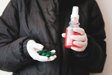 girl in protective gloves holds an antiseptic with pills. close-up