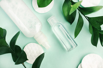 Beauty treatment products on pastel blue background with fresh green natural leaves, plastics bottle of facial toner top view, herbal skin care, eco hygiene.