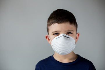 A caucasian male child wearing a face mask, the concept of flatten the curve stay home during pancemic of coronavirus.