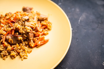 Traditional Uzbekistan pilaf on the rustic background. Selective focus. Shallow depth of field.