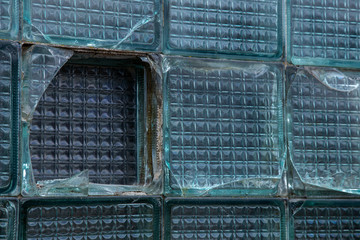 A window in a wall of broken glass blocks in a house destroyed after an accident. Creative trendy vintage background broken glass blocks